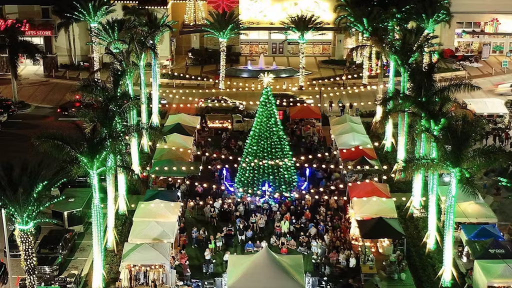 Large Night Market surrounded by illuminated palm trees and string lights.