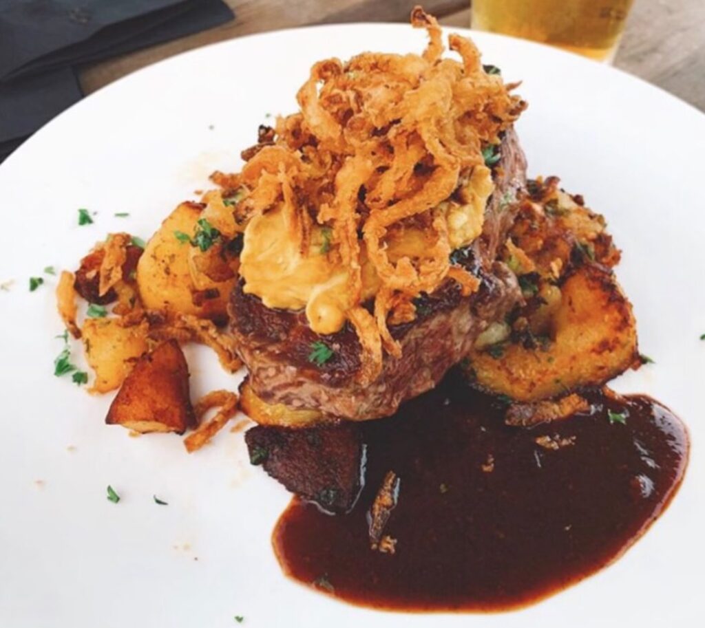 steak, onions, and gravy on a white plate. 