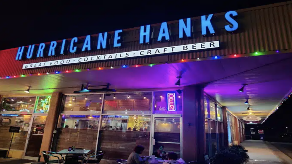 restaurant in a strip mall bathed in neon lights with tables out front